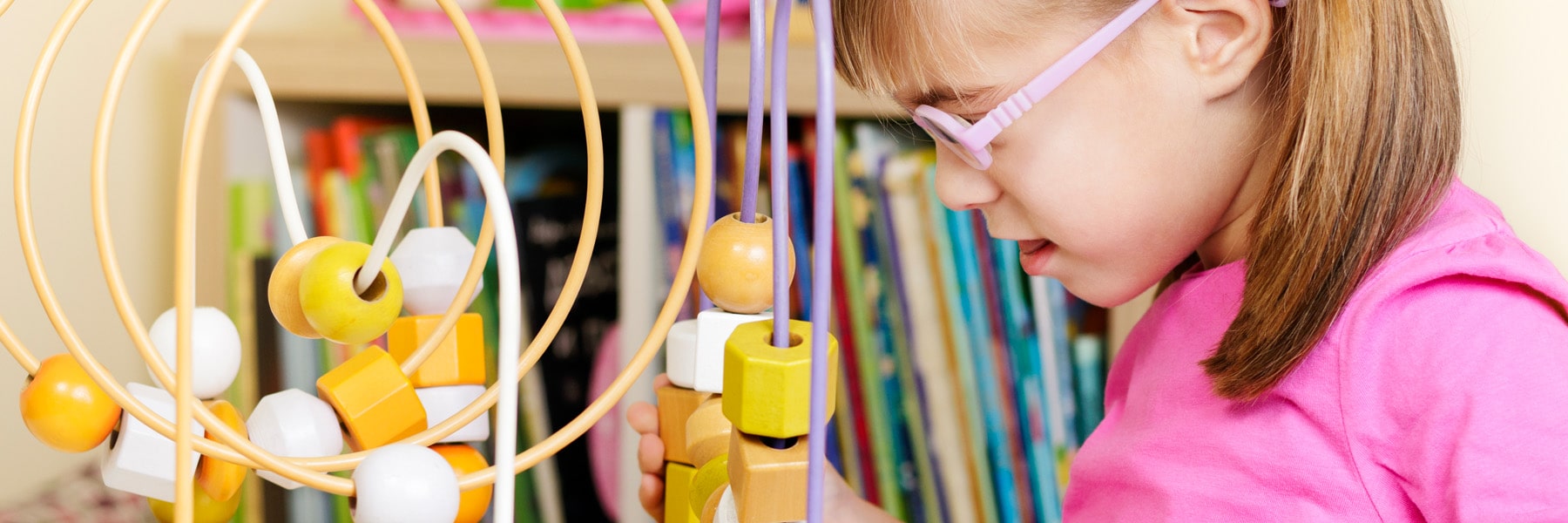close up of toddler with pink eye glasses and circular abacus toy
