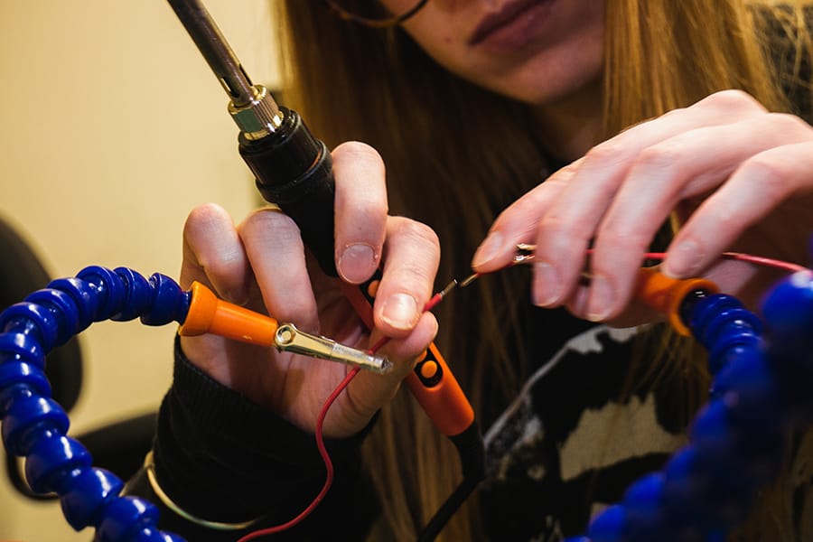 Student uses tools to connect circuits.