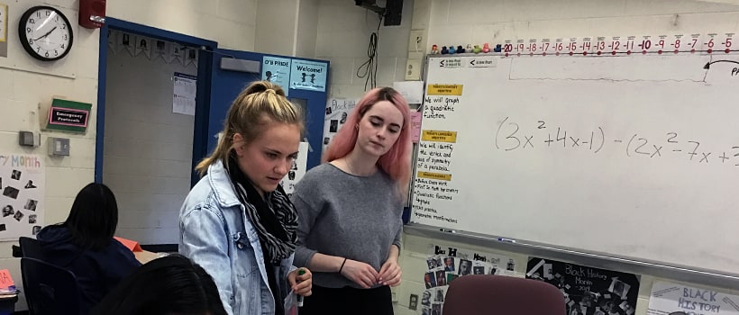 Two female students standing at a whiteboard