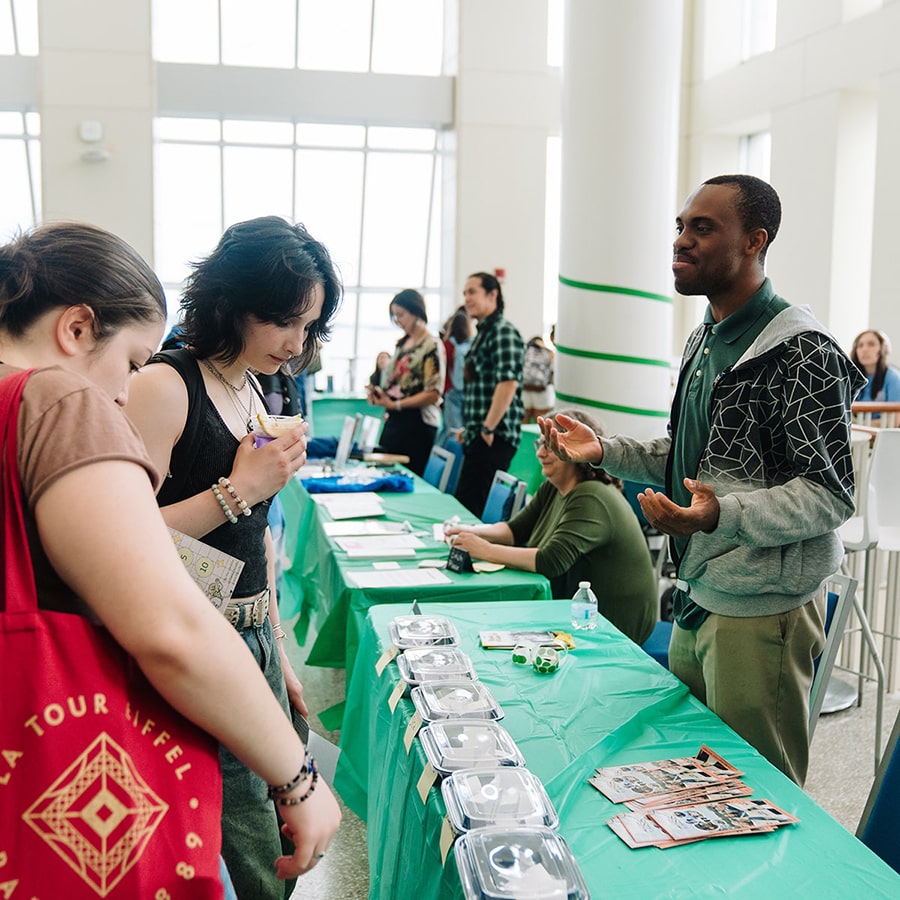 Students speaking and looking at table display at Walk with GRACE event.