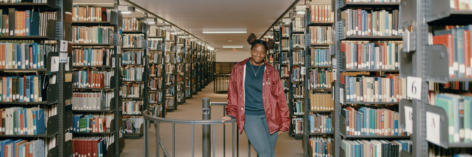 Student standing in library stacks