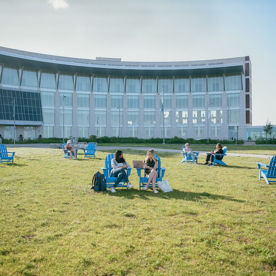 Student on Beacon Lawn in Blue Chairs