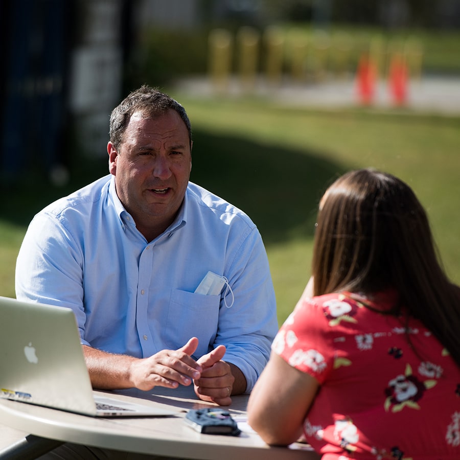 staff consults student with laptop outside