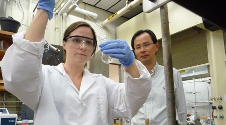 woman conducting an experiment in a lab under the watchful eye of a faculty member