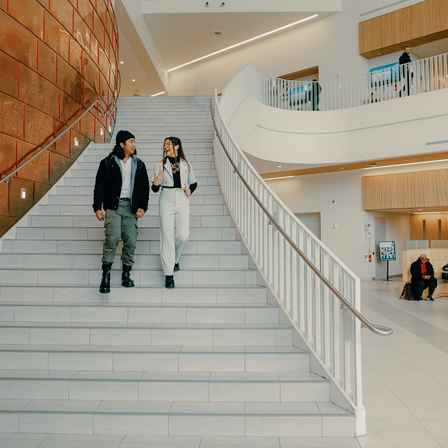 2 Students walk down grand stairs in UHall