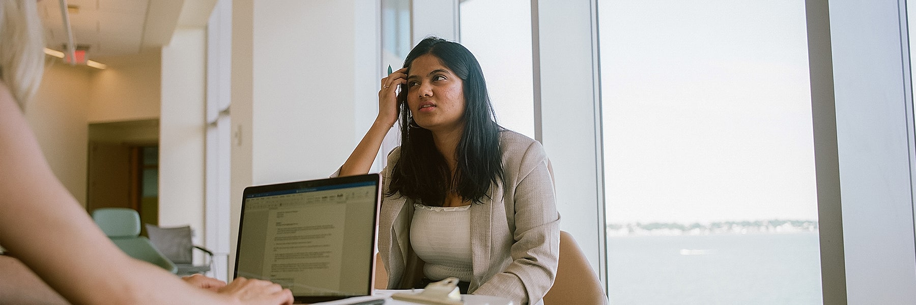 Two girls work together on a laptop inside at Umass Boston.