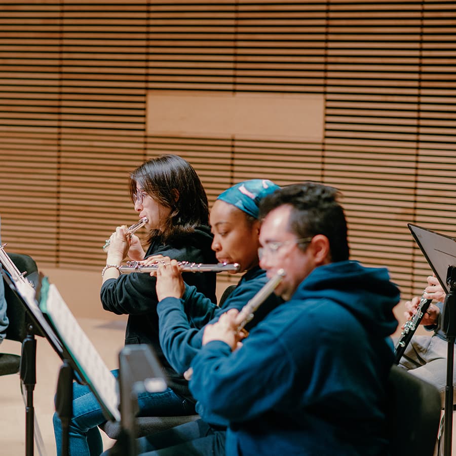 Students rehearse orchestra playing flutes.