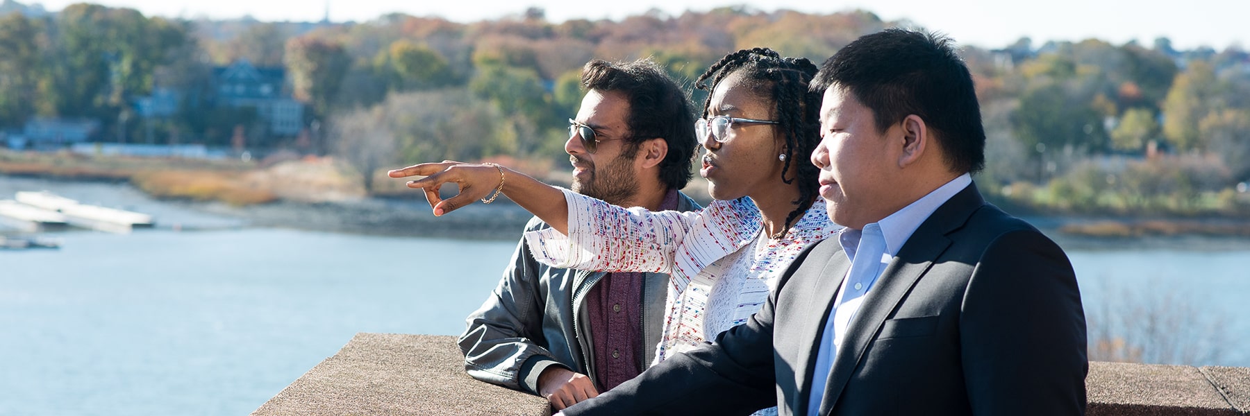 Three graduate students look over Savin Hill cover from terrace on campus.