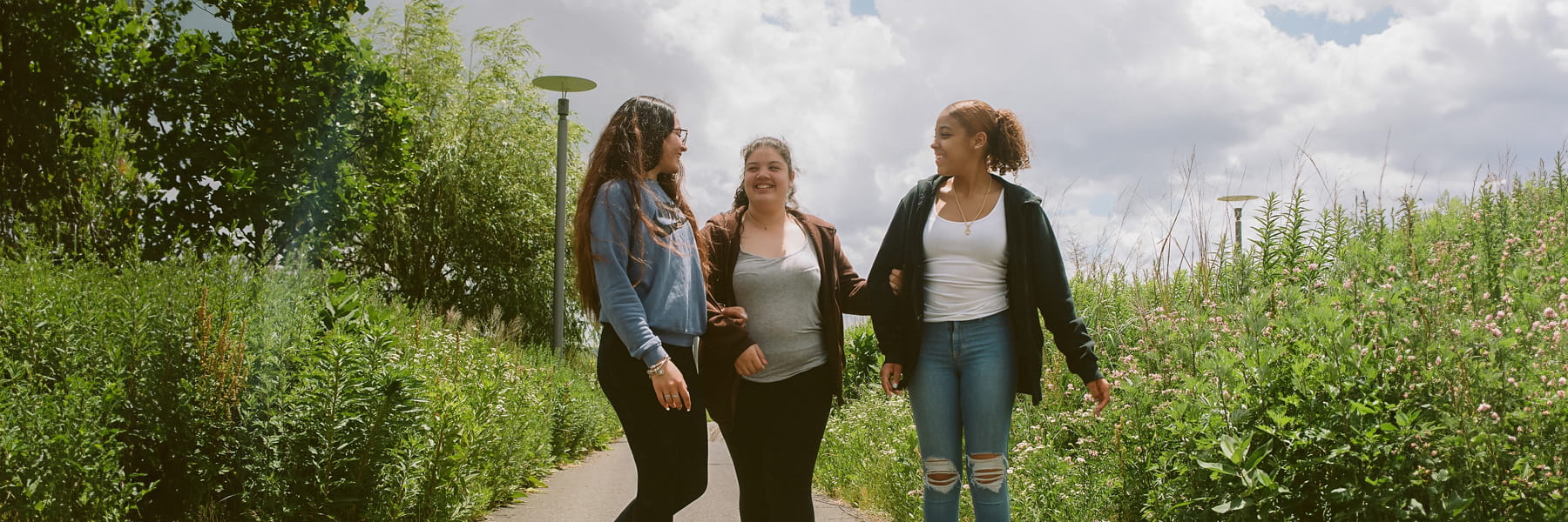 Three students walk on harborwalk.