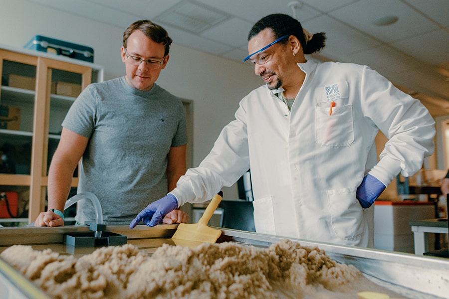 Admissions two graduate students examine water table in lab.