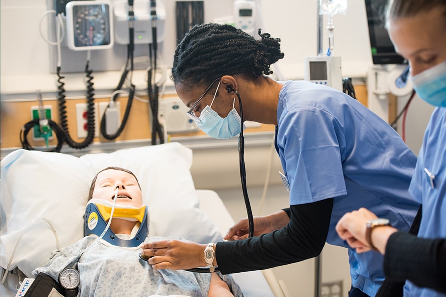 Nursing student treats dummy in simulation lab.