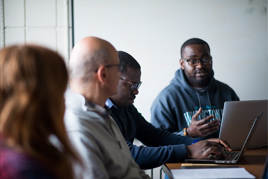 Students talk in a seminar sitting around a table.