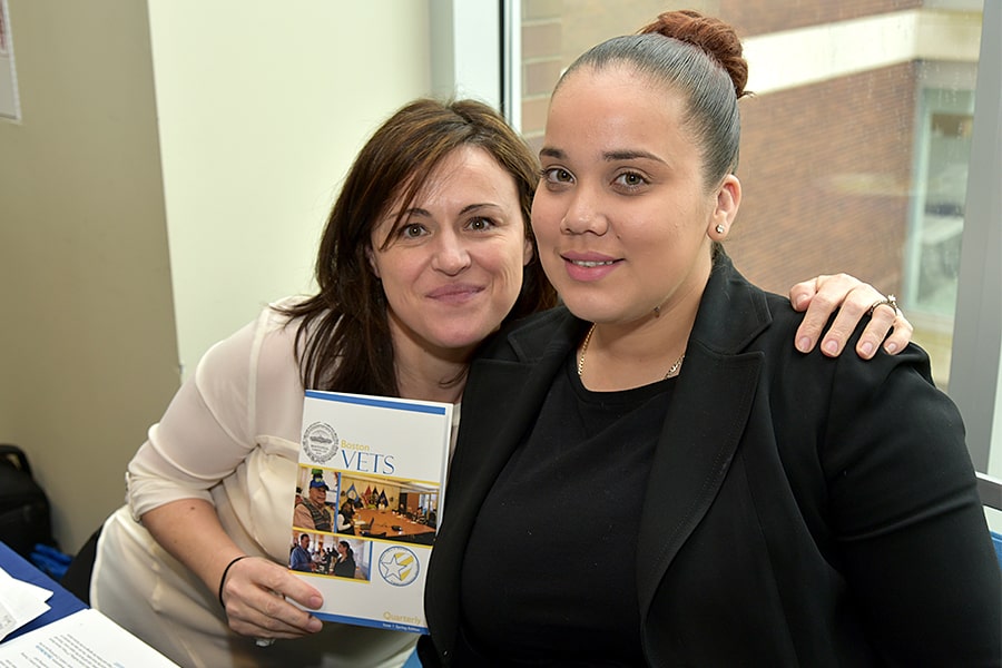 Two female veterans hold up a veterans brochure.