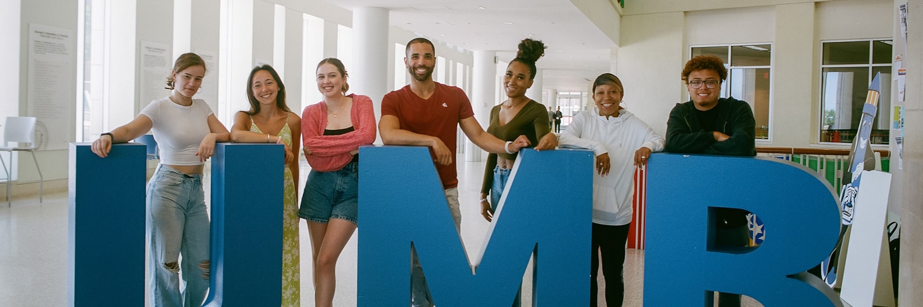 Students pose with sculptural UMB letters in Campus Center.
