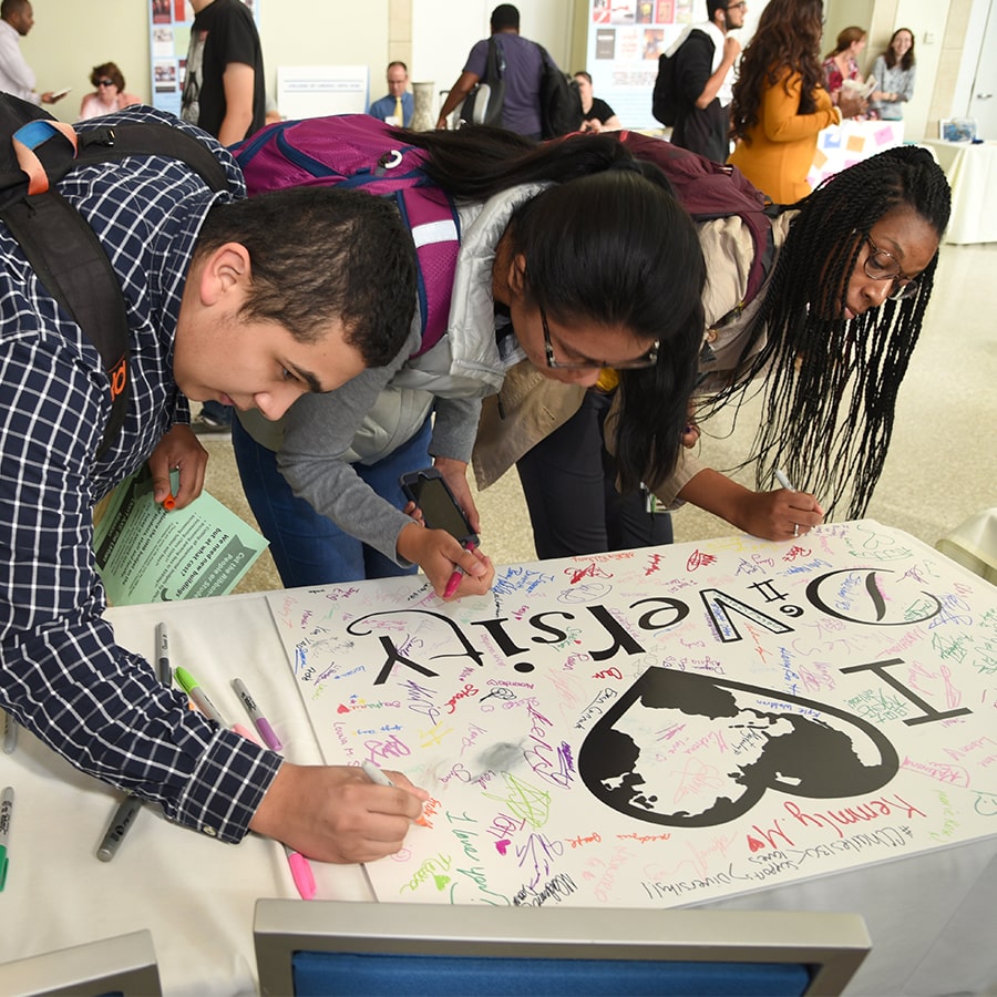 Students sign diversity heart poster.