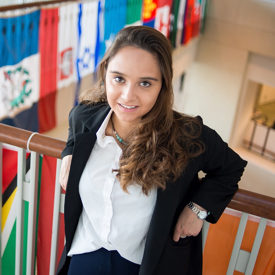 International student poses in front of flags at Campus Center.