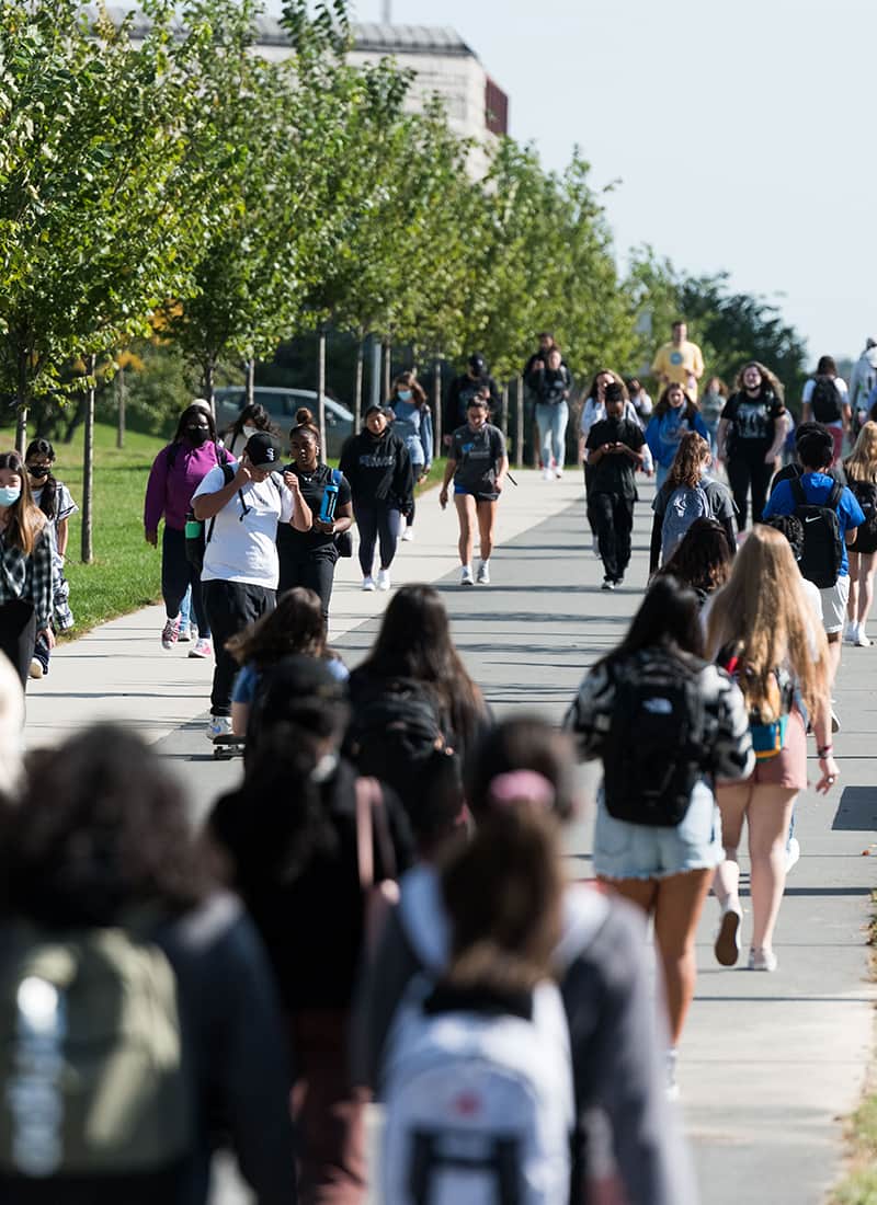 Crowd Students walk along walkway toward Uhall.