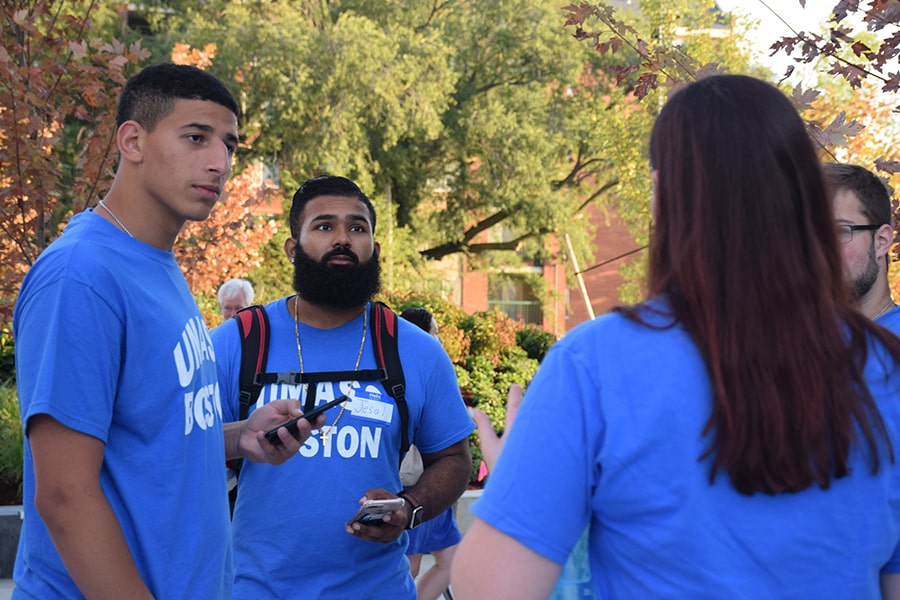 Students in UMass Boston t-shirts talking on move-in day by residence halls.