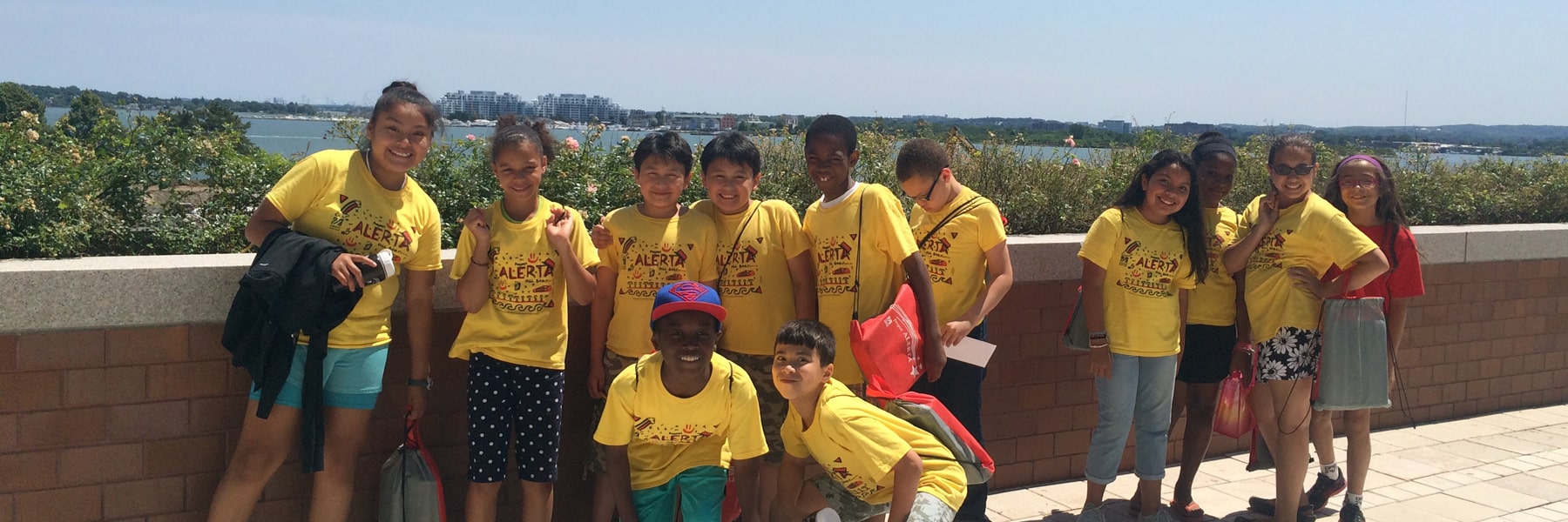 students from program crouch for group photo wearing yellow t-shirts with program branding