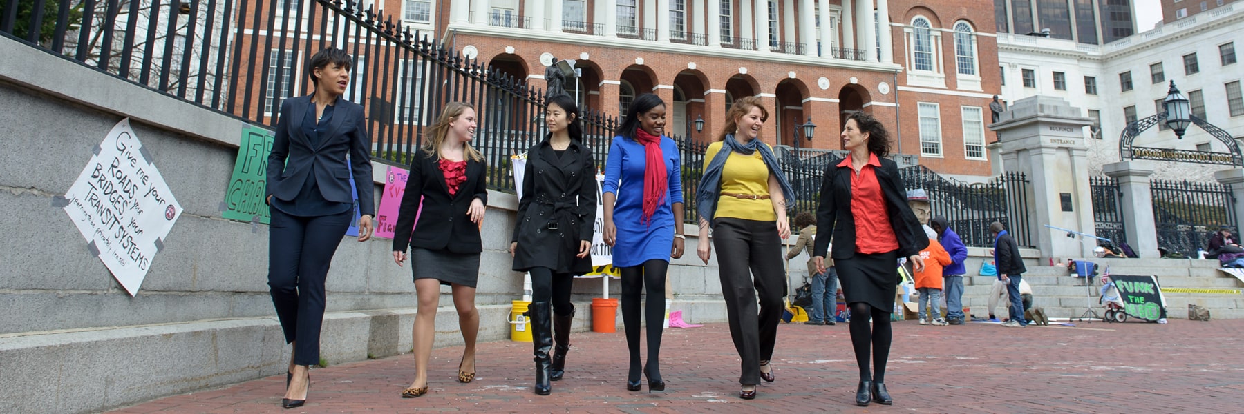 women in casual business attire walking in front of Massachusetts State House
