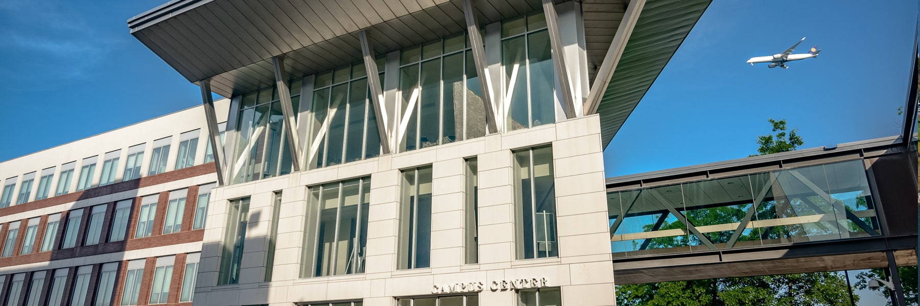 exterior of UMass Boston Campus Center blue sky and airplane in background