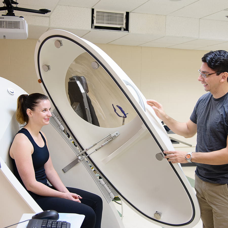 Trainer opening oval door on piece of fitness equipment.