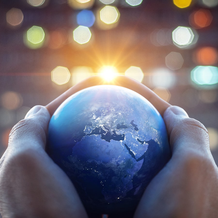 Hands hold a globe with special effects background.