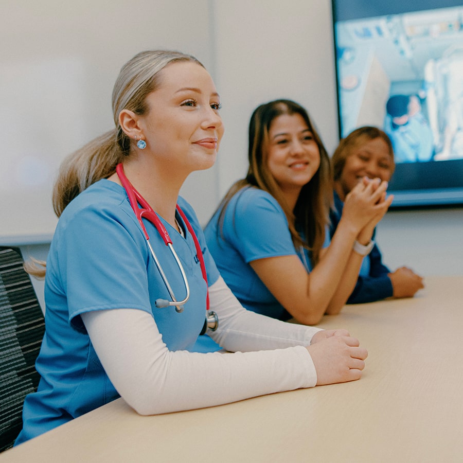 nursing students around conference table with image on presentation screen