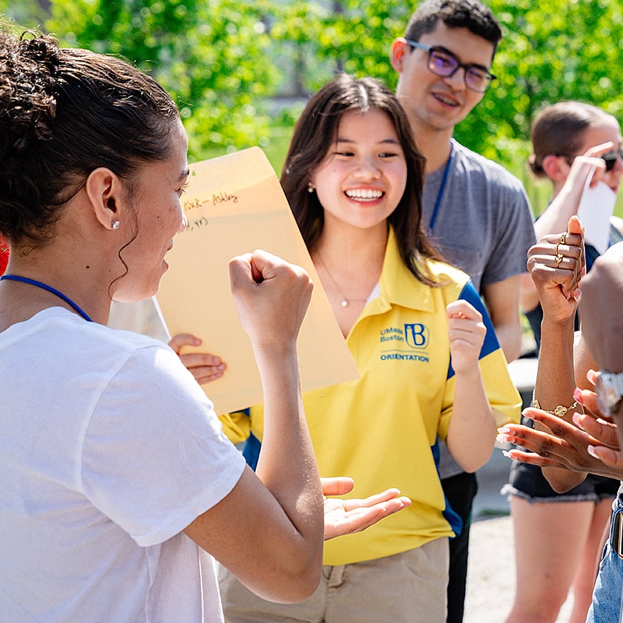 Students gather round an orientation leader outside at UMass Boston.