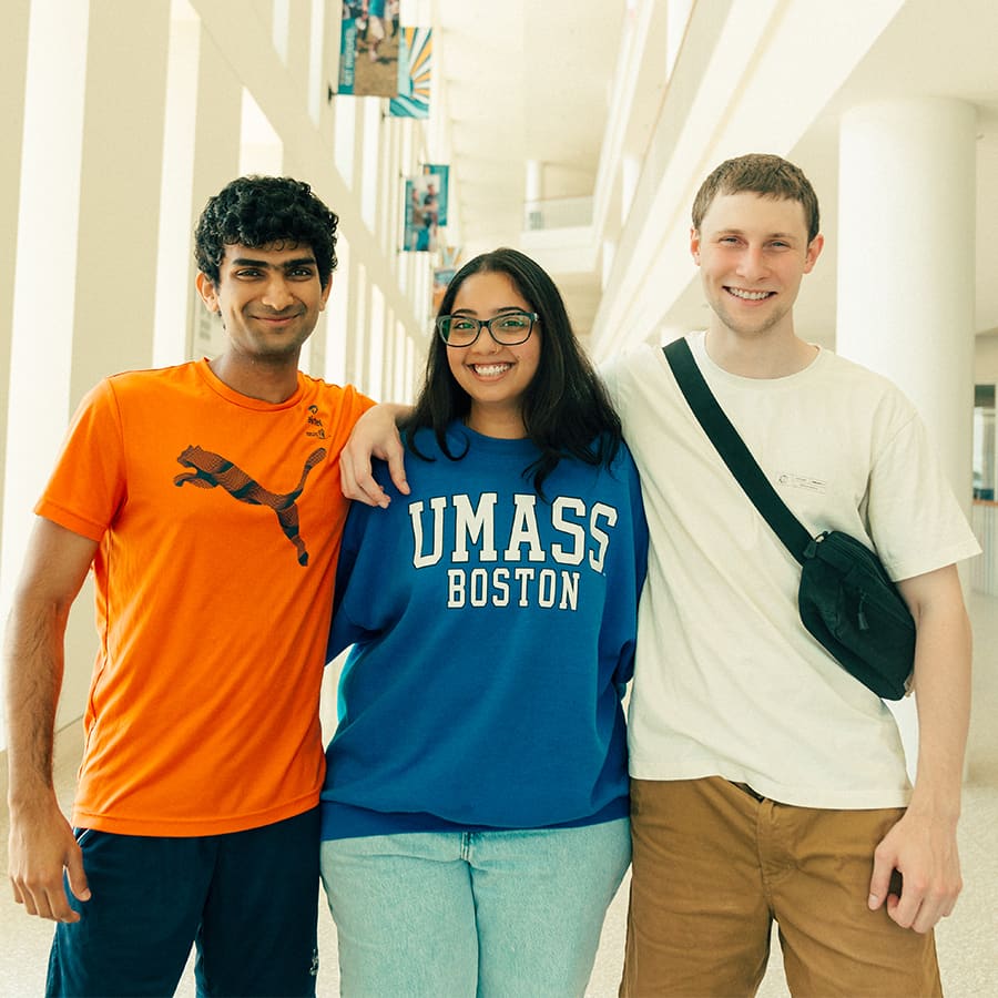 Three UMass Boston students, a woman and two men, smiling