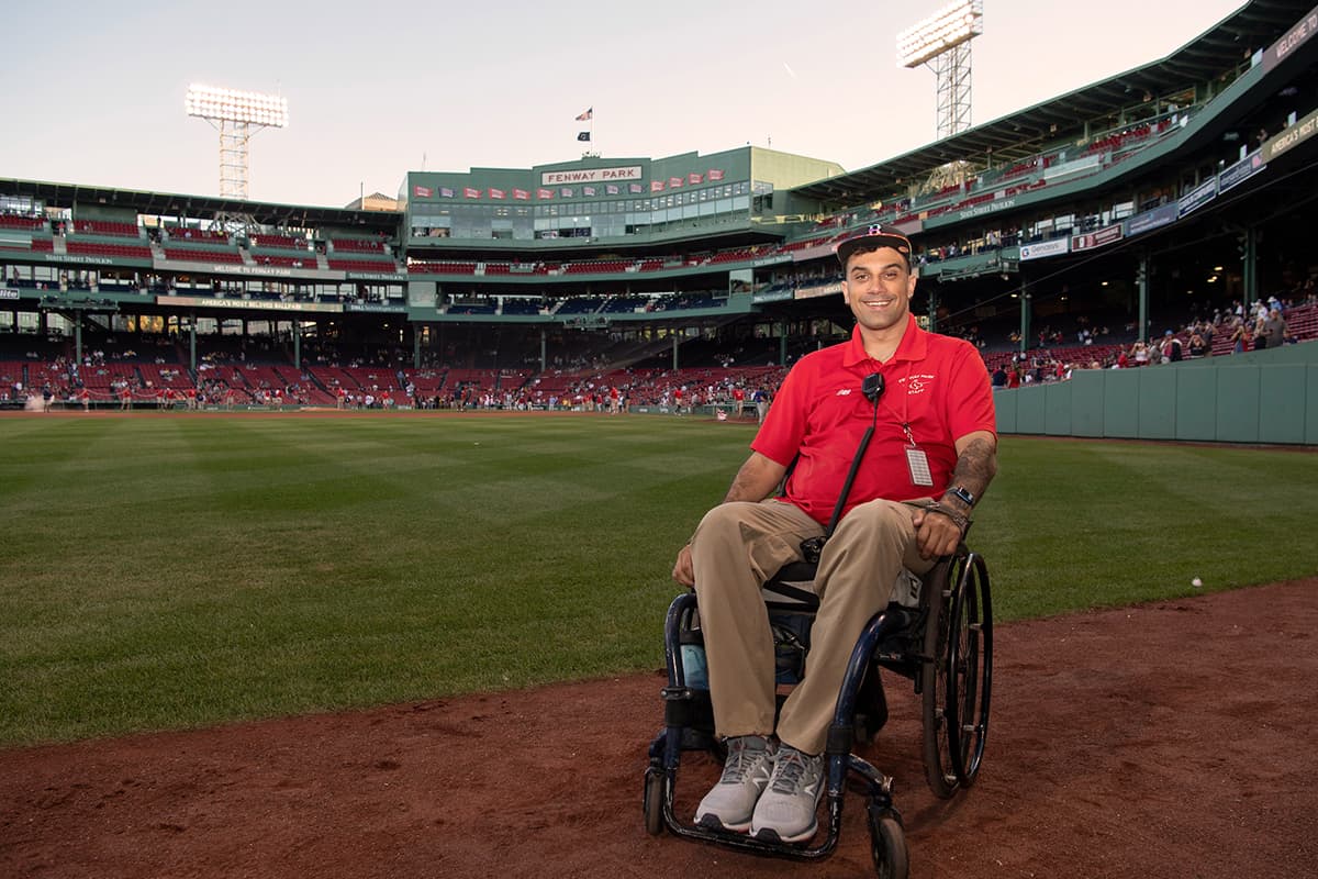 Sitting in his wheelchair on the field at Fenway park, Stefan wears a Red Sox employee shirt.