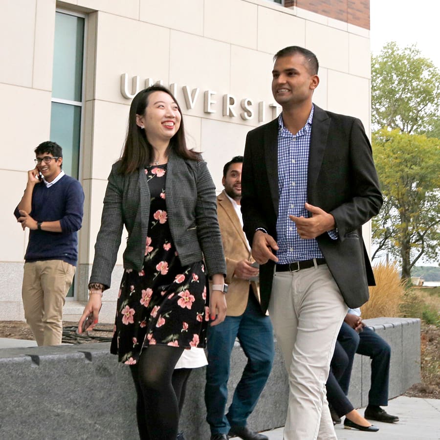 two mba students walk in front of university hall.