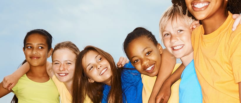Five elementary-age children smiling with arms around eachother