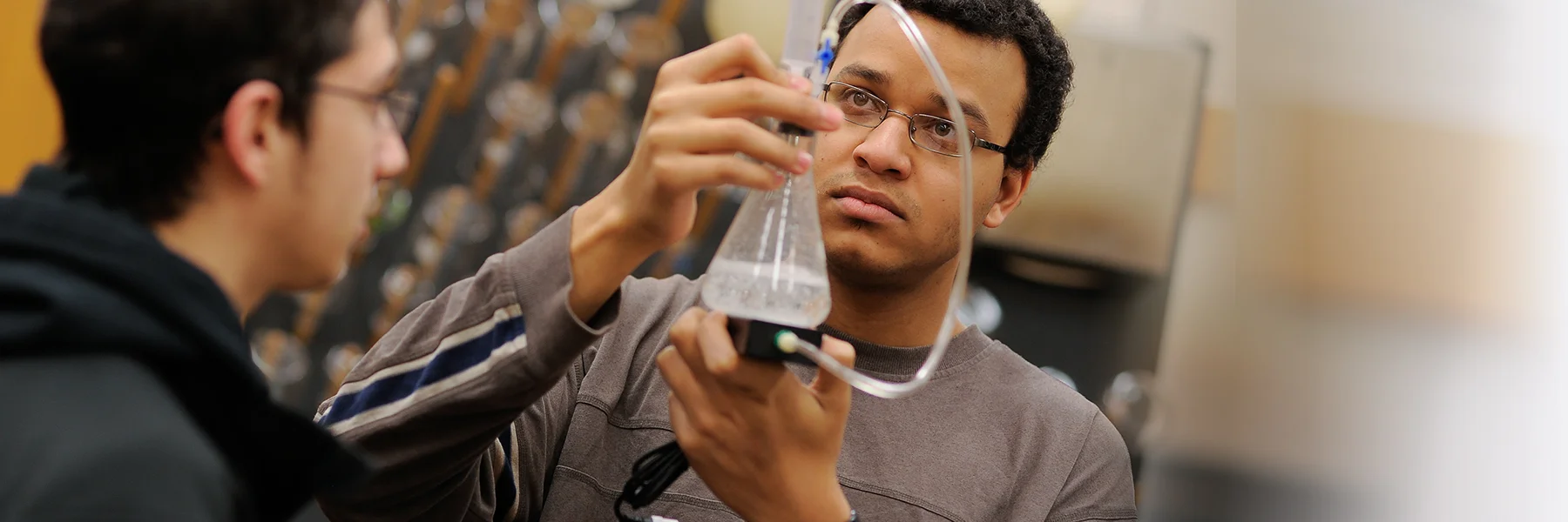 Student holds flask of liquid in the lab.