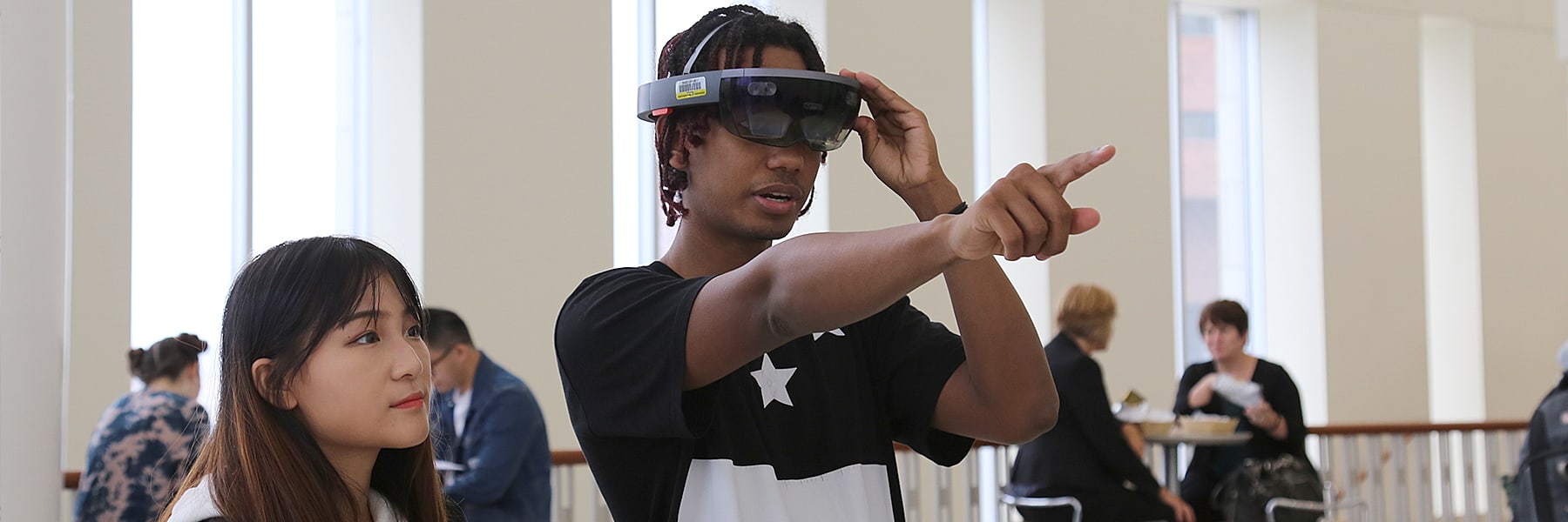 Student wears a VR headset and demos it in the Campus Center.