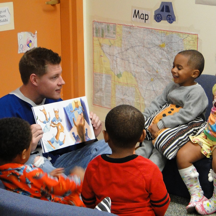Hockey player reads book to young kids in an early childhood education setting.