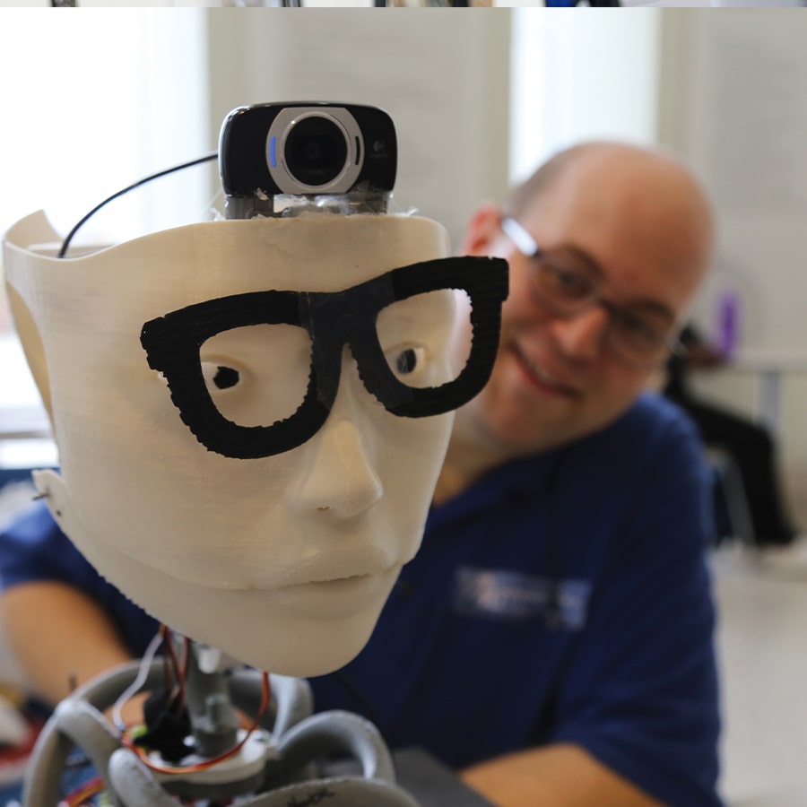 Photo of John Mazzarella with a robot head photo by Lisa Link.