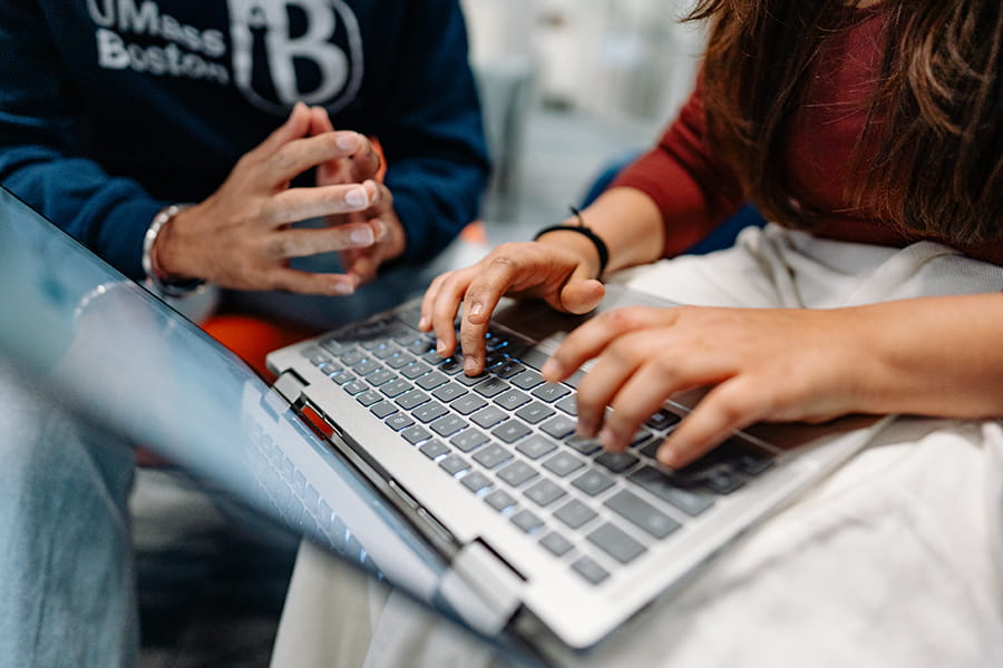 Students typing on laptop.