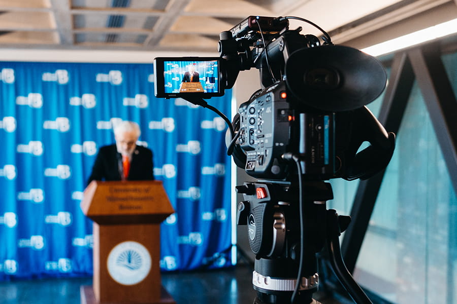 Camera recording Chancellor Marcelo Suárez-Orozco speaking at podium.