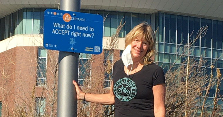 Senior Lecturer in Nursing Linda Chiofar stands by a sign on the Grace Trail 