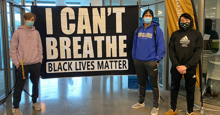 Students stand by an I Can't Breathe, Black Lives Matter poster.