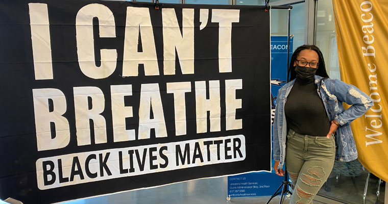 Female student stands by an I Can't Breathe, Black Lives Matter sign. 