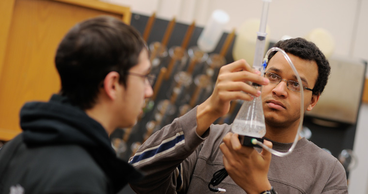 Students hold up a beaker in a chemistry lab. 