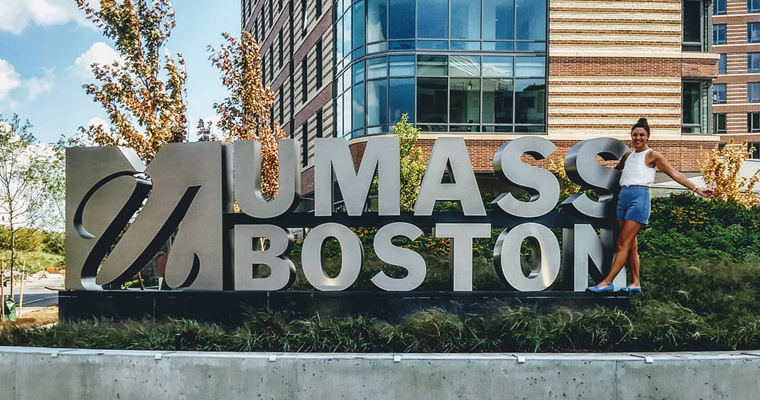 Kelsey Edmond in front of the UMass Boston sign 