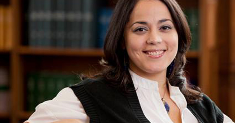 Headshot of Assistant Professor Lorena Estrada-Martinez in front of a wooden bookshelf. 