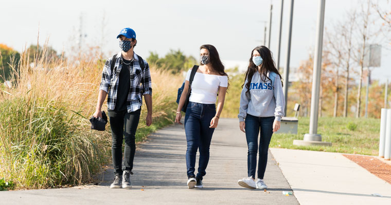 Students wearing masks walk the HarborWalk 