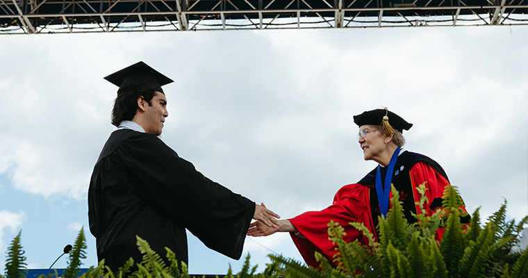 Senator Warren shakes hands with a graduate 