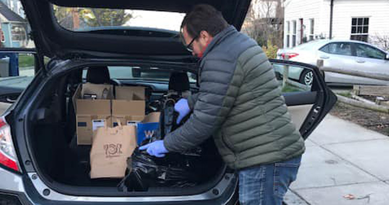 Francesco Peri loads PPE into the trunk of a car. 