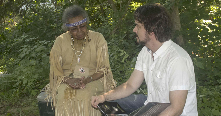 Steve Silliman and a person in native dress look at a book