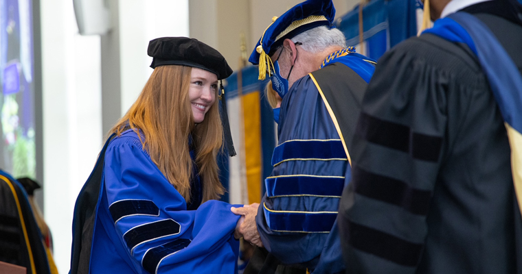 Doctoral student receives degree at hooding ceremony. 